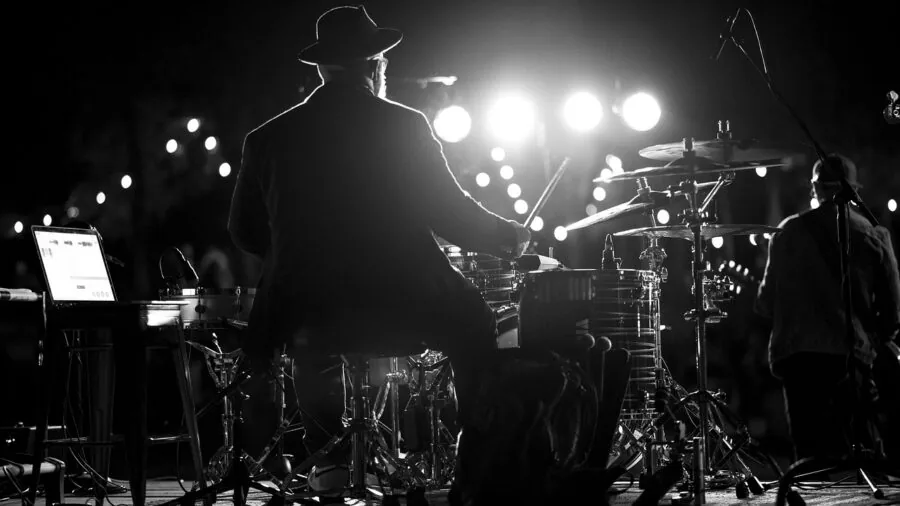 Musician playing acoustic drum kit during live performance with focused intensity