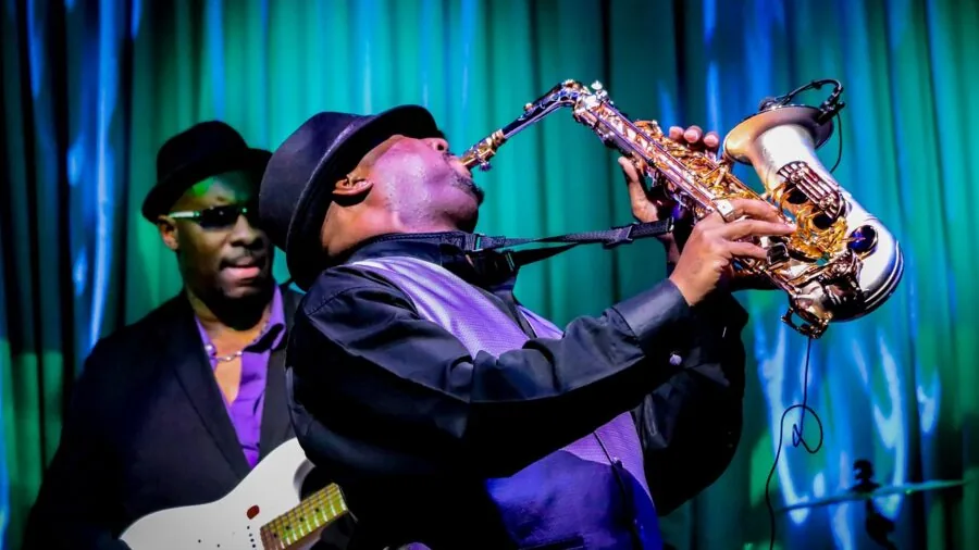 Musician playing saxophone with focused expression during live performance