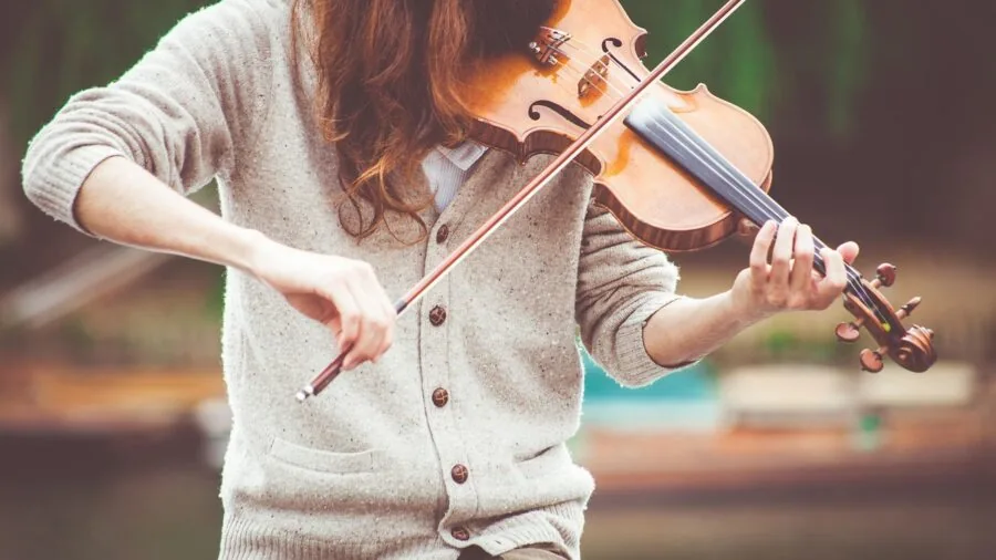 Musician practicing with various string instruments including guitar, bass, and ukulele in home studio setting