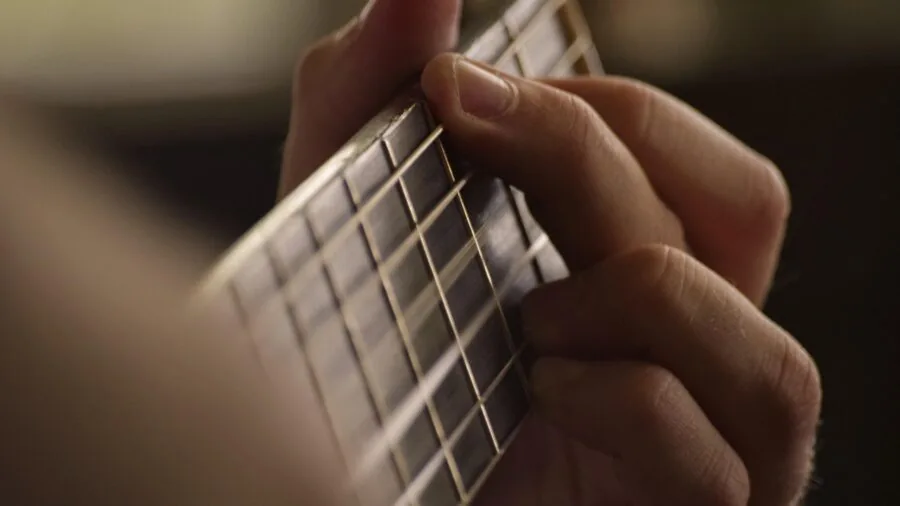 Musician's hands holding and adjusting a guitar capo during practice session