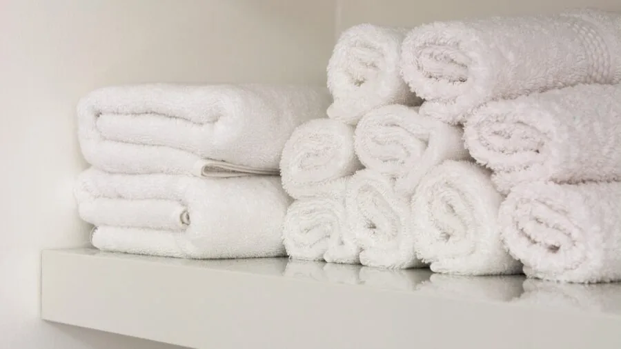 Neatly folded towels organized on bathroom shelf demonstrating quality and longevity of bath linens