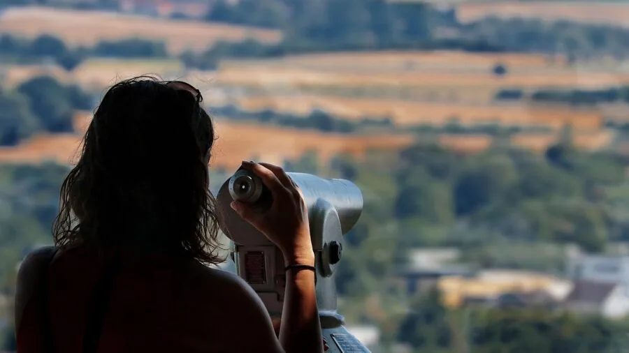 Observer using optical equipment to view distant landscape in natural daylight