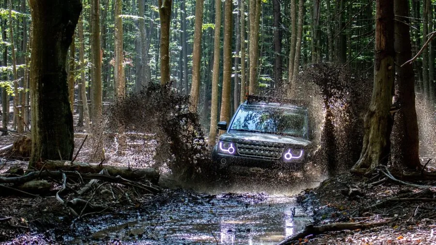 Off-road vehicle navigating through muddy, snowy terrain in winter conditions