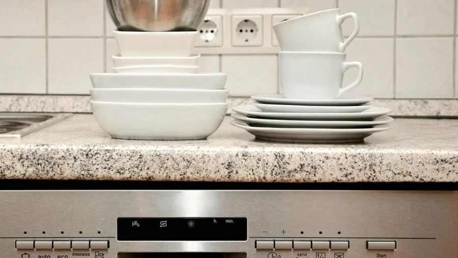 Open dishwasher being loaded with clean dishes and containers in a modern kitchen