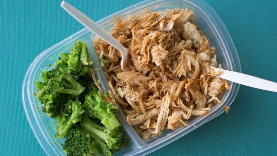 Open lunch box with fresh food containers and vegetables, showing organized meal prep and food storage