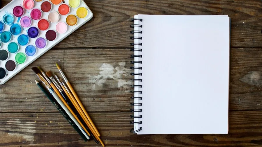 Organized collection of colorful papers arranged on a wooden desk for creative projects