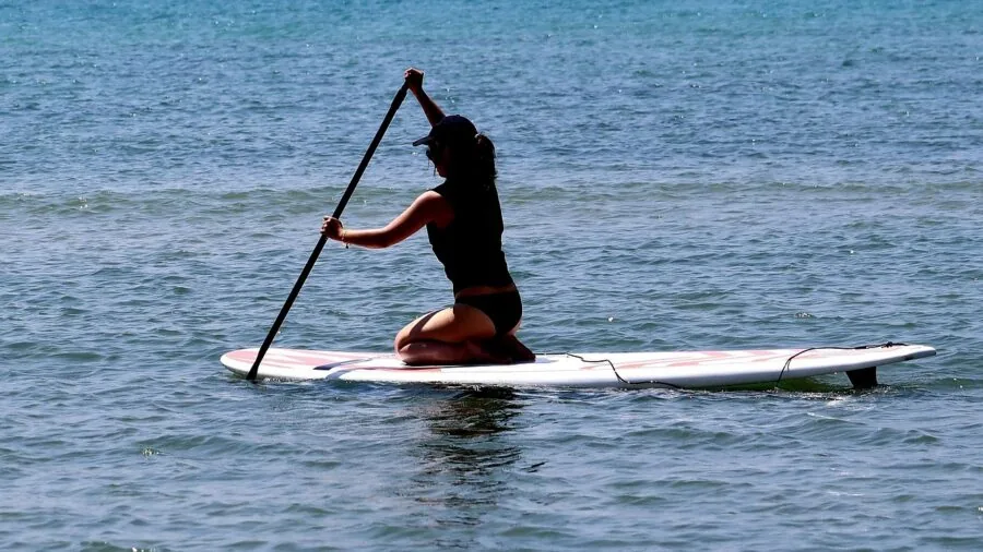 Organized SUP accessories including pump, paddle, leash and carry bag on wooden surface