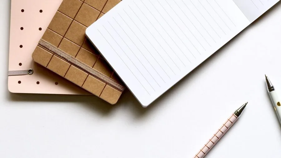 Organized writing desk with papers, notebooks, and supplies spread across spacious wooden surface for focused work