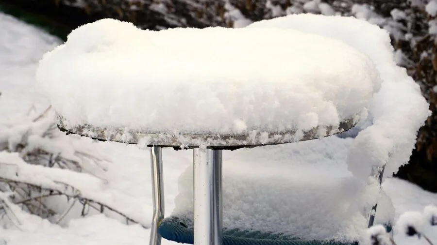 Outdoor patio furniture protected with weatherproof cover during snowy winter season