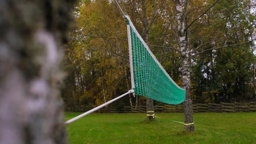 Outdoor volleyball net in bright sunlight showing wear and weathering from UV exposure and use