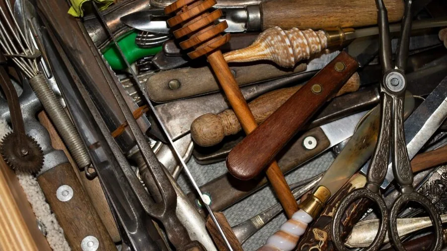 Overhead view of an overflowing kitchen drawer with unused cookware and utensils crammed inside