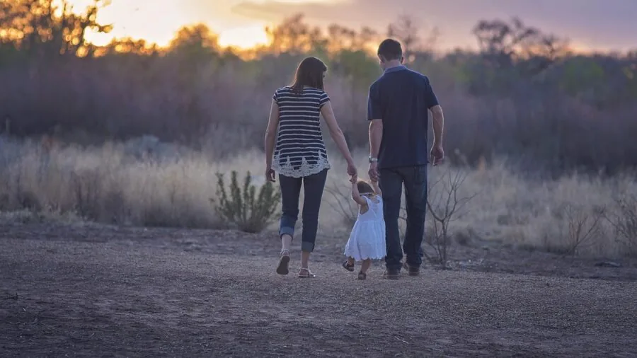 Parent and toddler walking outdoors on a sunny day in a natural setting