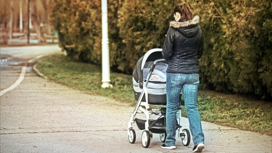 Parent bundling baby in warm stroller during cold weather outdoor walk