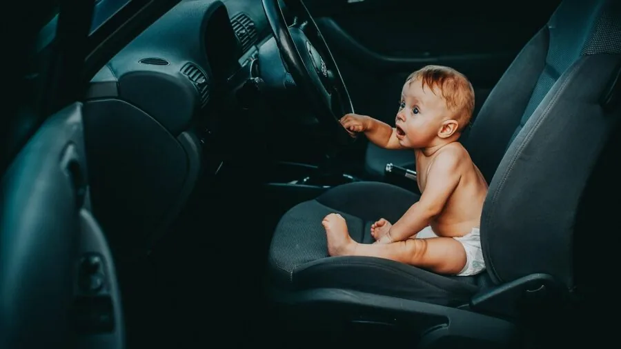 Parent carefully installing infant car seat base in vehicle during family road trip preparation
