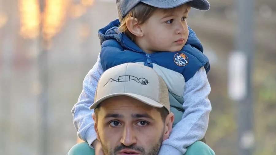 Parent carrying a neutral-colored bag while walking outdoors with child