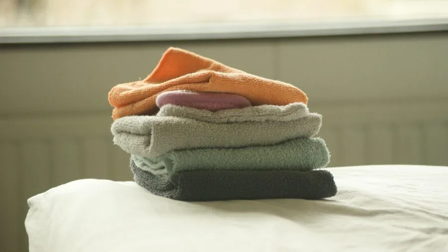 Parent doing laundry with baby towels in washing machine at home