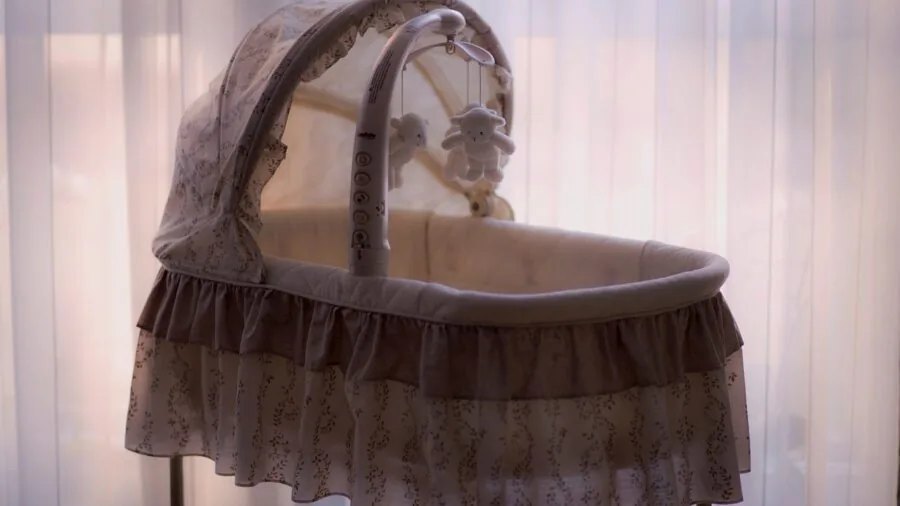 Parent examining sturdy steel frame of bedside bassinet in bedroom setting