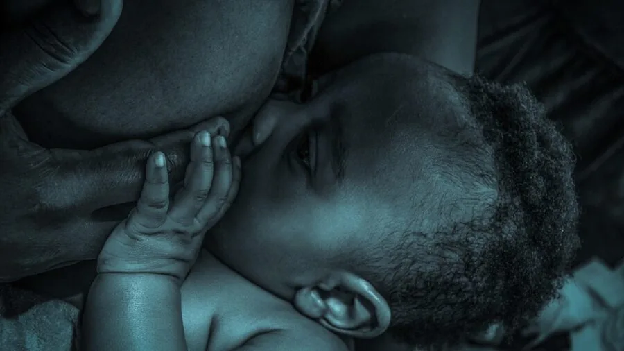 Parent gently feeding newborn baby bottle, showing nurturing care during infant feeding time