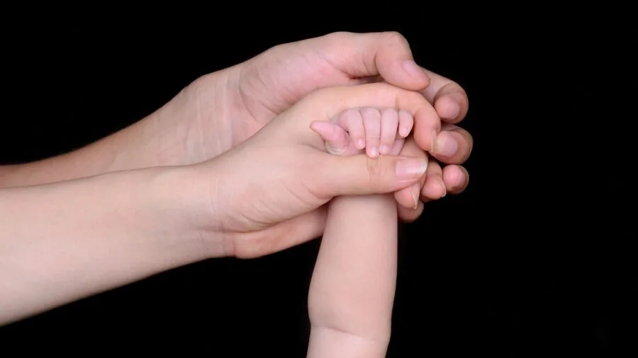 Parent holding infant while nursing, demonstrating proper posture and back support during breastfeeding