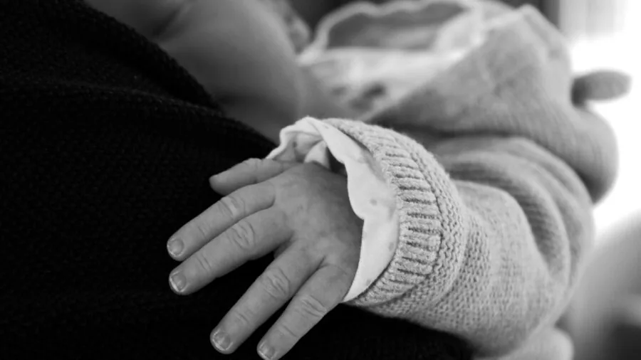 Parent monitoring sleeping infant in dark bedroom at night for safety and comfort