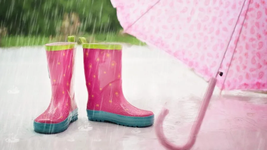 Parent pushing stroller through rainy weather with child, demonstrating outdoor durability needs