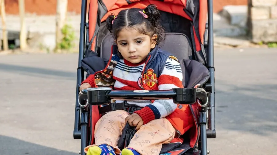 Parent pushing stroller with toddler securely fastened during outdoor walk in park