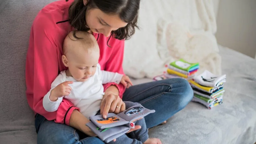 Parent reading a cloth book with baby on lap during playtime, showing affordability and value of soft books