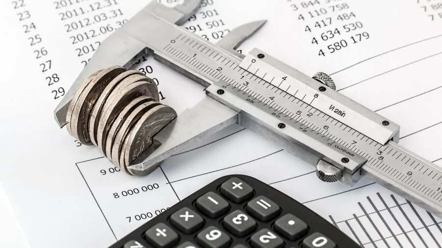 Parent reviewing financial budget and expenses at home desk with calculator and notebook