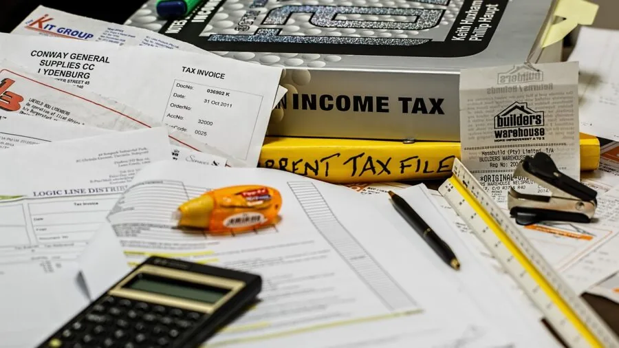 Parent reviewing household budget and expenses at home desk with calculator and documents