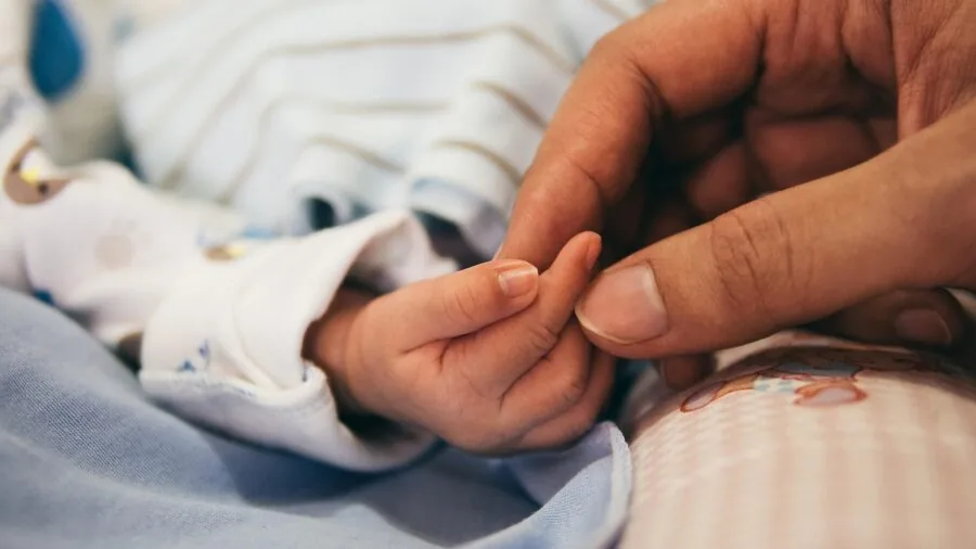 Parent safely feeding infant with glass bottle during daytime bonding moment
