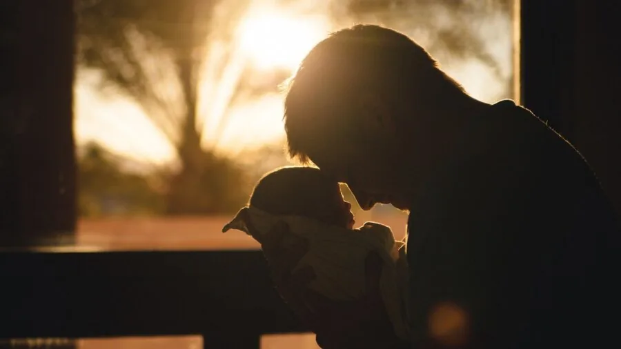 Parent tenderly comforting feverish baby during illness, gentle caregiving moment