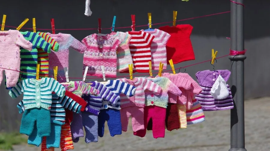Parent washing and folding baby clothes in a bright laundry room with natural light