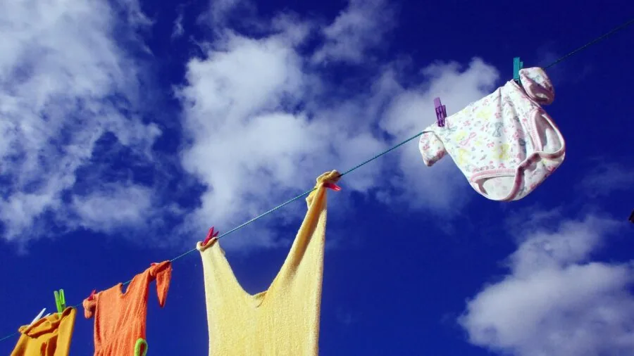 Parent washing toddler clothes in washing machine, demonstrating durable fabric care for children's clothing