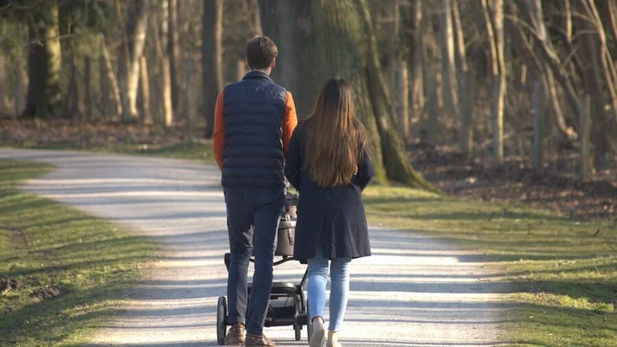 Parent wearing backpack while pushing stroller with toddler, hands free and balanced
