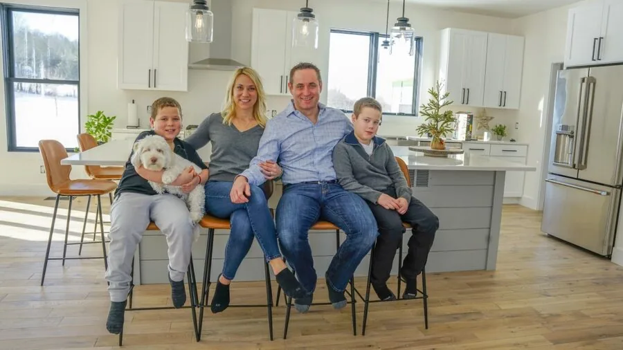 Parent wiping down kitchen counter while child and pet play nearby in modern home