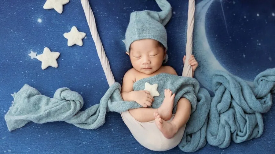 Peacefully sleeping infant in soft-lit nursery with gentle mobile casting shadows overhead
