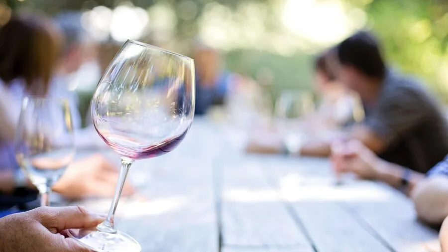 People enjoying wine together at a dinner table in warm candlelight
