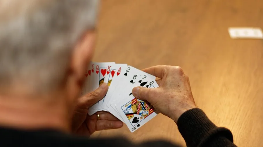 People shuffling and playing cards together at a table during a casual game night