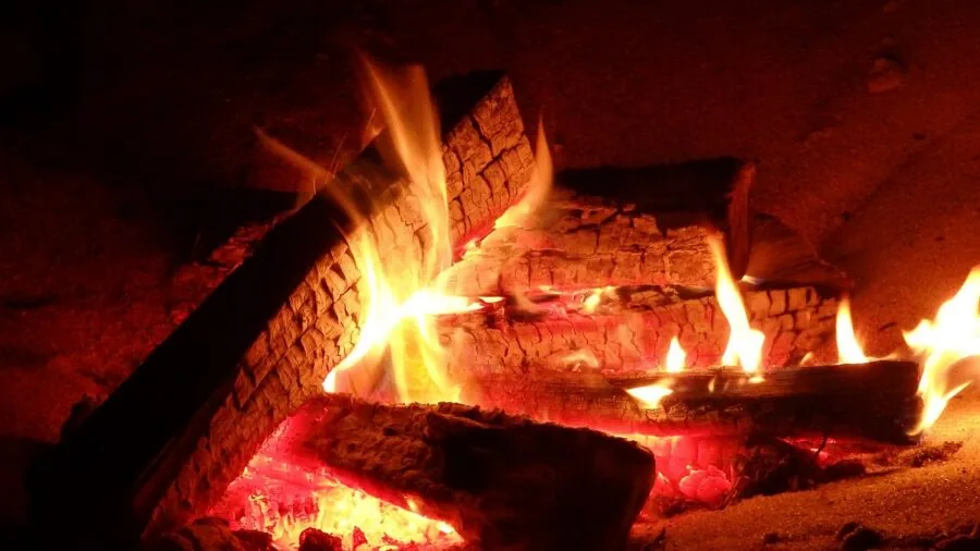 People sitting around a glowing wood-burning fire pit at dusk, enjoying warmth and conversation outdoors