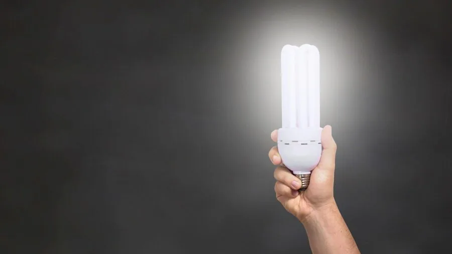 Person adjusting a dimmer switch to control warm lighting in a modern home interior