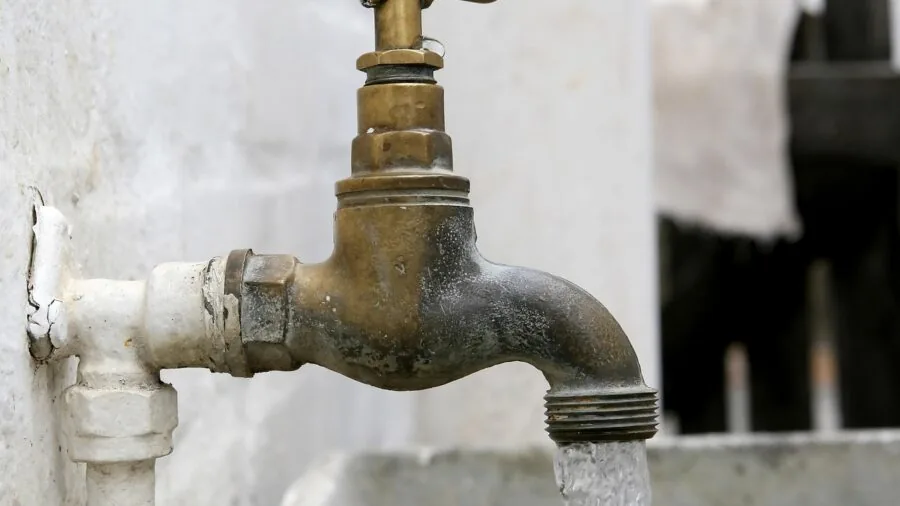 Person adjusting a valve connection on plumbing system, hands-on maintenance scene
