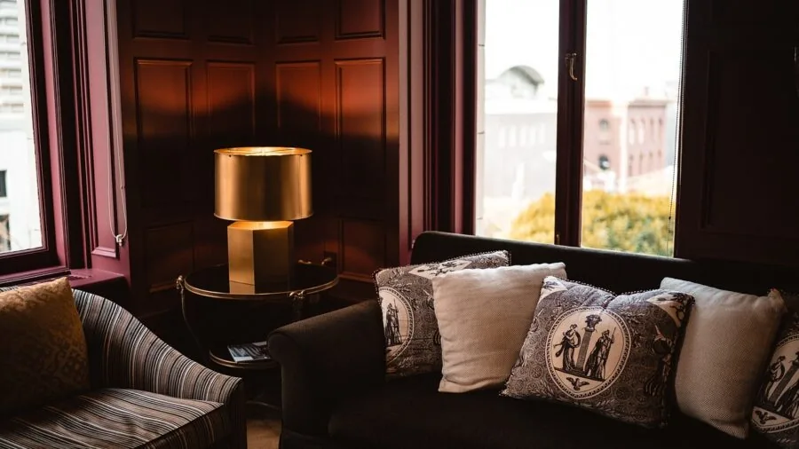Person adjusting and fluffing decorative pillows on a comfortable couch in a bright living room