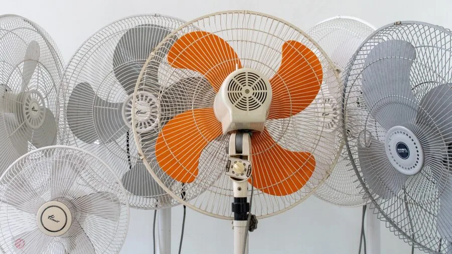 Person adjusting cooling fan near gaming console setup in home entertainment space