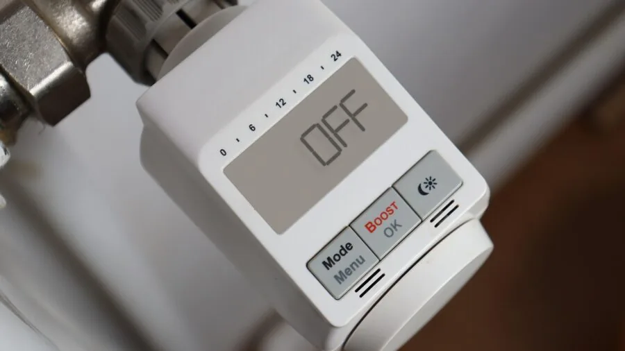 Person adjusting home temperature control on wall, demonstrating smart home privacy and data collection awareness