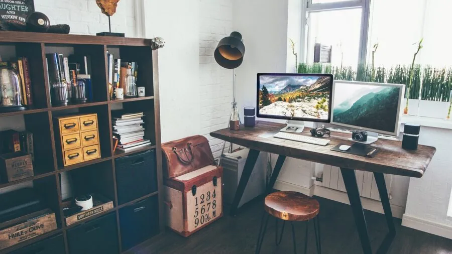 Person adjusting monitor stand at organized computer desk workspace