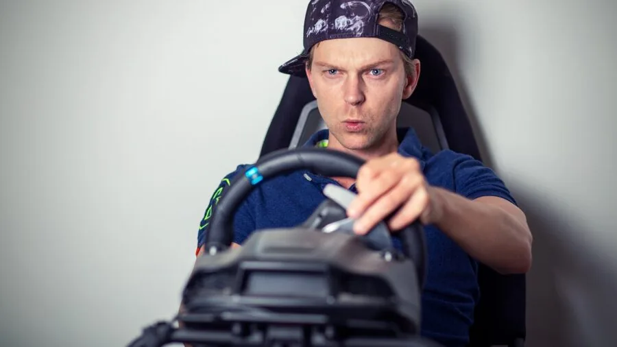 Person adjusting pedals on racing simulator setup with focused hand positioning