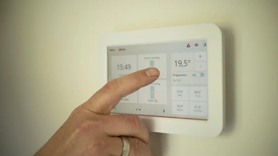 Person adjusting portable air conditioning unit in living room during hot summer day