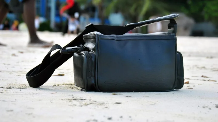 Person adjusting security strap on single suitcase during travel preparation
