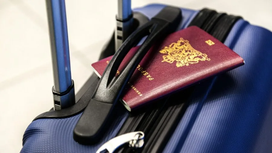 Person adjusting telescoping handle on rolling suitcase during airport travel