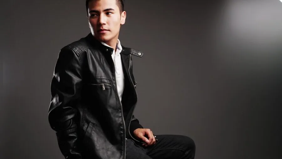 Person applying conditioner to aged leather jacket in natural light, demonstrating leather care maintenance